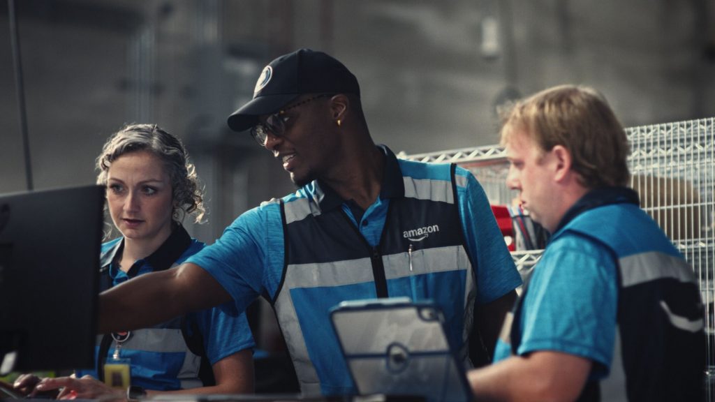 Livreur Amazon portant les Smart Delivery Glasses connectées, illustrant le nouvel investissement de 1,9 milliard de dollars dans le programme DSP et ses technologies IA en 2027