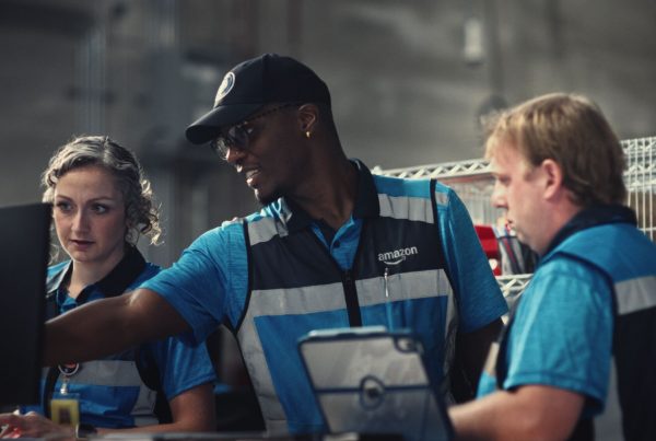Livreur Amazon portant les Smart Delivery Glasses connectées, illustrant le nouvel investissement de 1,9 milliard de dollars dans le programme DSP et ses technologies IA en 2027